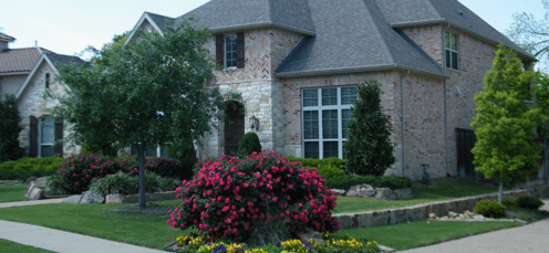 Professionally designed residential landscape featuring colorful flower beds, manicured lawn, and custom landscape design by Trimlawn Landscape Services.